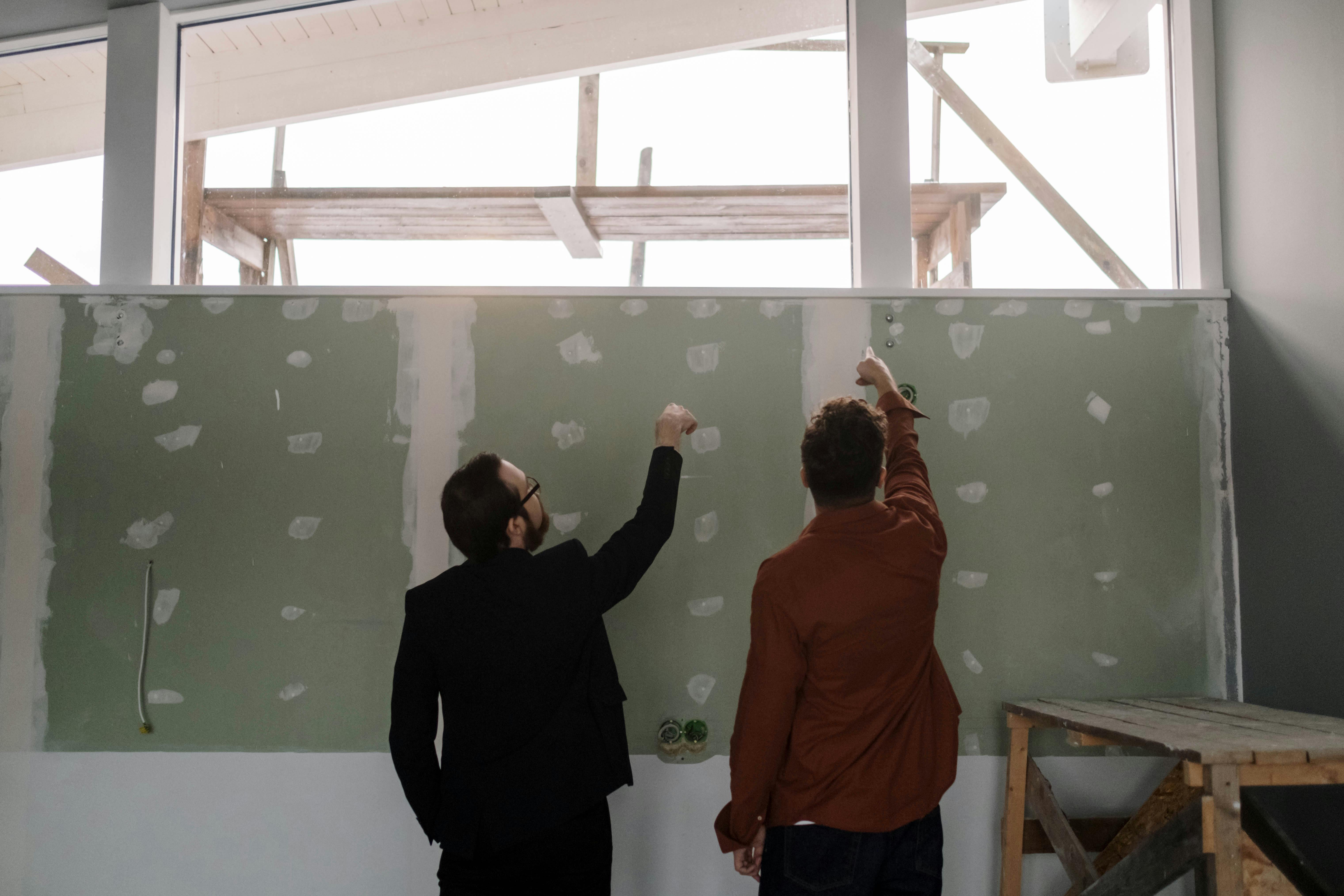Two construction professionals examining current status of as-built interior space with exposed framing and large windows
