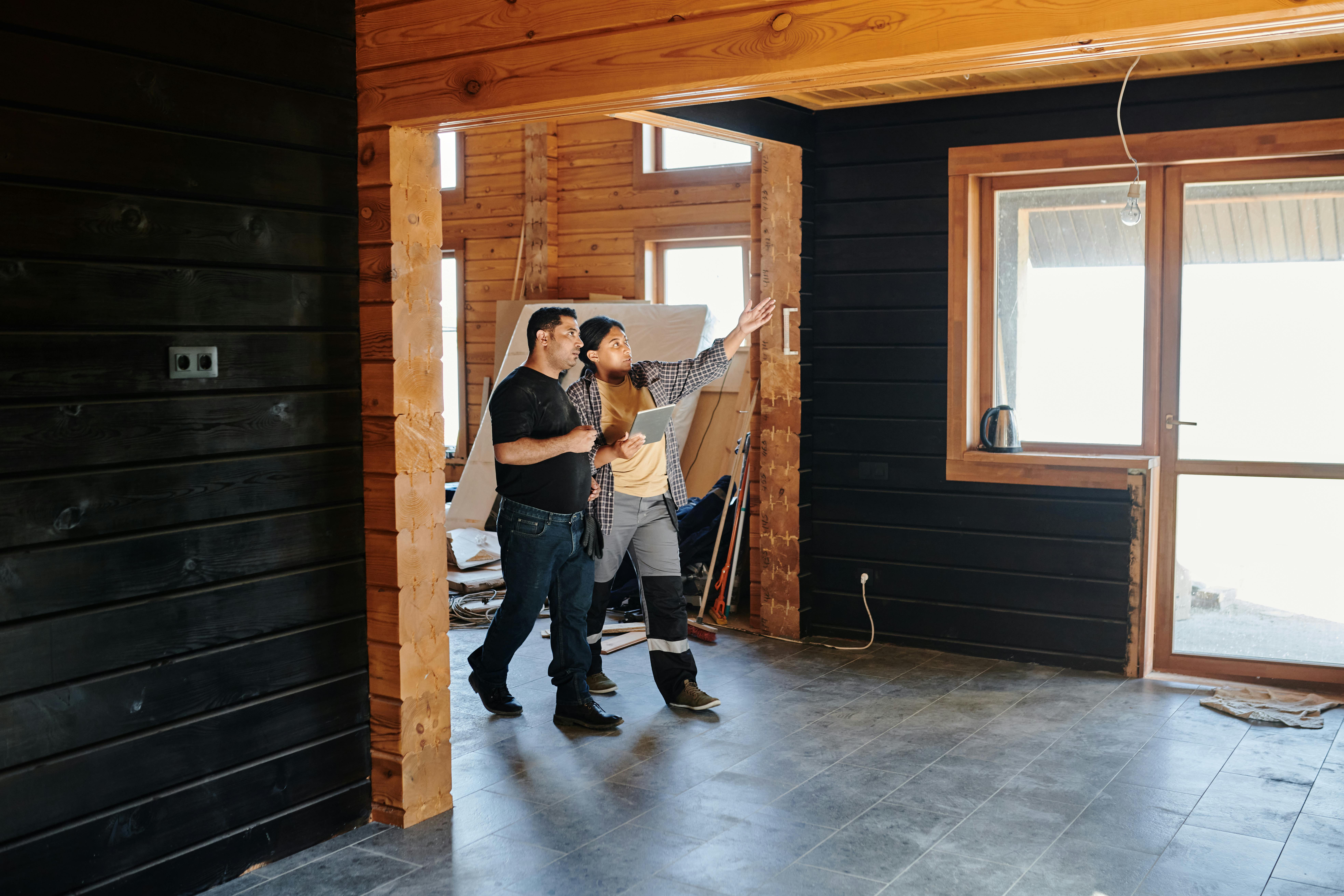 Three professionals reviewing renovation plans inside a room with wooden walls and bright windows