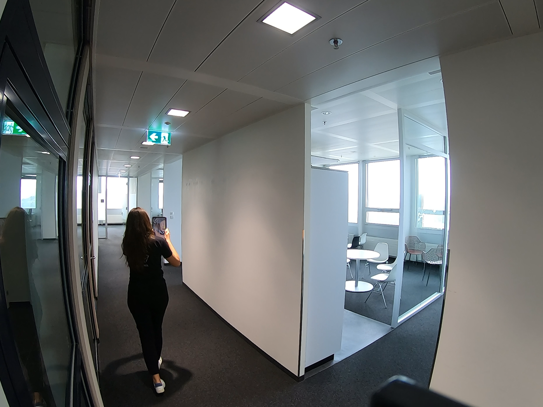Person walking through an empty office building, while documenting the site with MAVO 3D as point cloud.